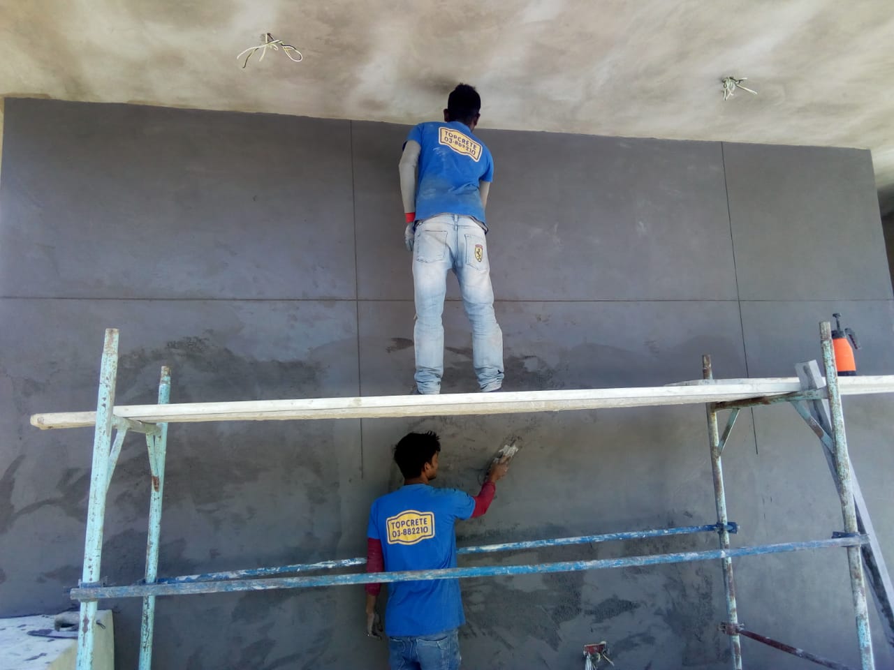 Workers plastering a wall on scaffolding