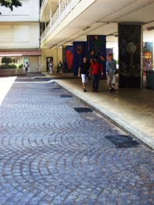 People walking under building with colourful murals