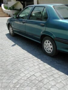 Green sedan parked on cobblestone driveway