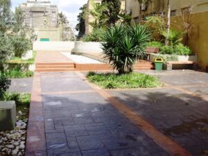 Urban garden with paved walkway and greenery.