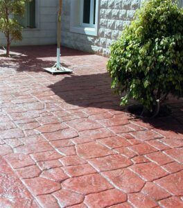 Red stamped concrete patio with bushes