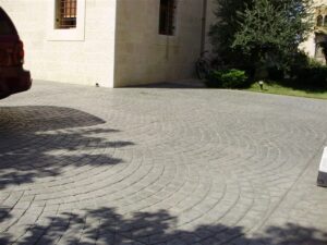Sunlit driveway beside stone building