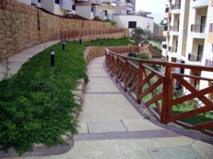 Curved walkway beside modern buildings and plants.