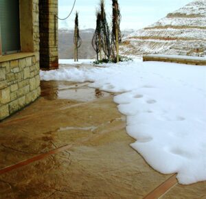 Footprints in snow on patio near hills