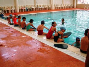 Kids sitting poolside with swim gear