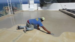 Person leveling concrete surface on roof