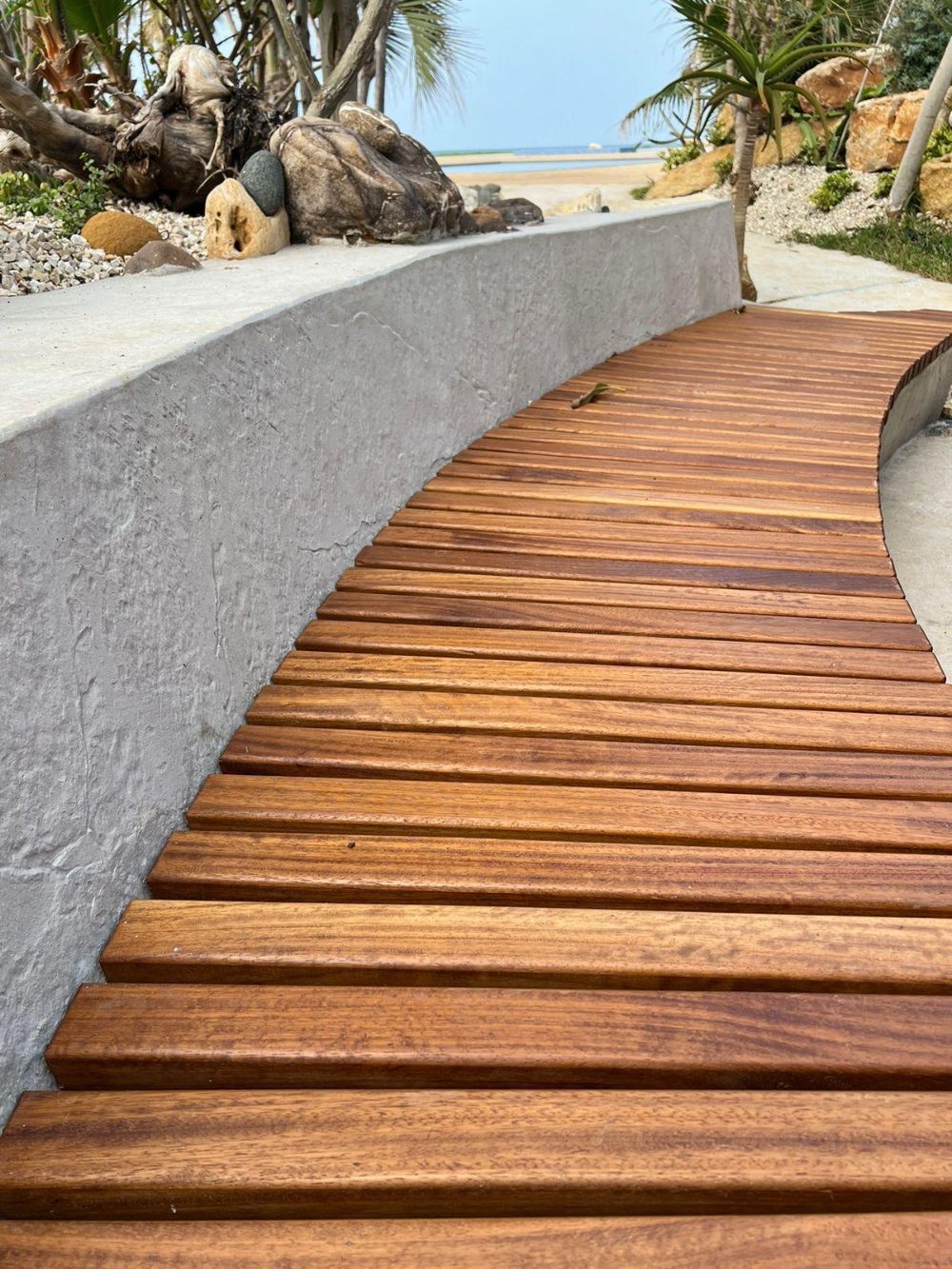 WallTex textured wall coating on a curved seafront retaining wall beside a timber boardwalk in Lebanon